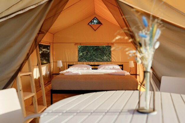 Interno di un'accogliente tenda glamping aperta con luce interna durante il tramonto Tenda da campeggio di lusso per vacanze estive all'aperto e vacanze Concetto di stile di vita