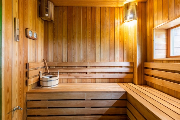 Interno di una classica sauna finlandese con finestra e ripiani in legno naturale