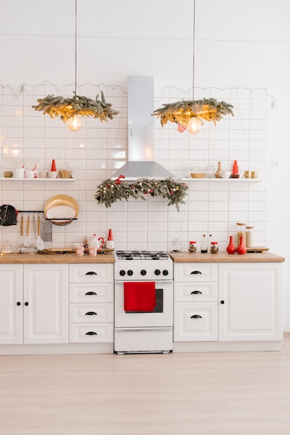 Interno di una cucina bianca chiara con elementi decorativi rossi luminosi in stile scandinavo decorati per Natale