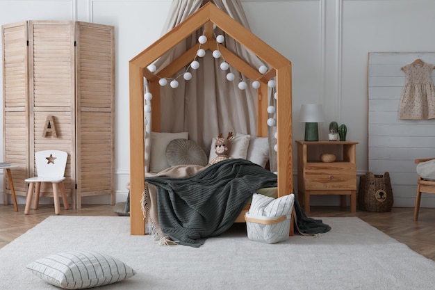 Interno elegante della stanza del bambino con letto di casa in legno