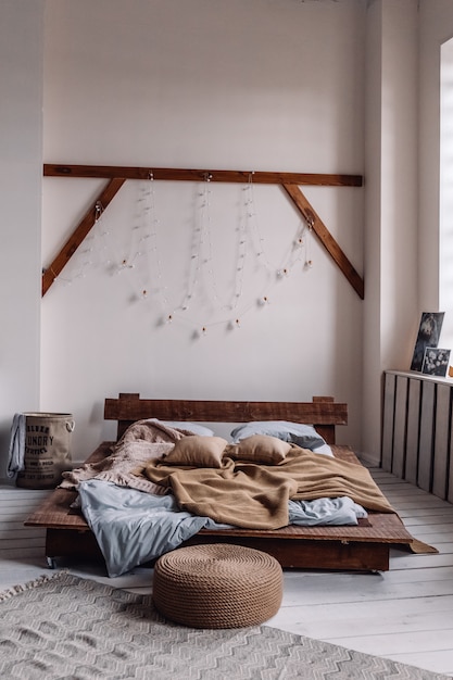 Interno hipster con letto minimalista e ghirlanda leggera