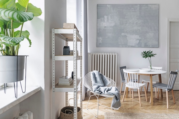Interno moderno del soggiorno nordico con divano grigio di design, tavolino, piante, accessori eleganti, decorazioni, tappeti e librerie in eleganti decorazioni per la casa