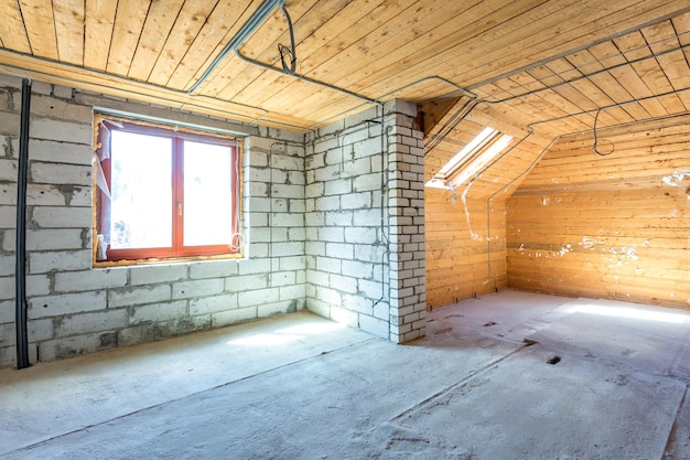 Interno vuoto in casa senza riparazione su pavimento in legno mansardato e muro di mattoni
