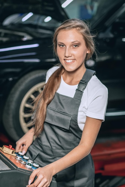 Interruttori idraulici su e giù, destra e sinistra in un garage per auto. Ragazza in una tuta nera e una t-shirt bianca con un telecomando nella stazione di servizio. concetto di riparazione dell'auto