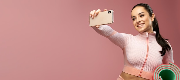 Intestazione del sito web di una giovane donna allegra con un tappetino da yoga che fa selfie