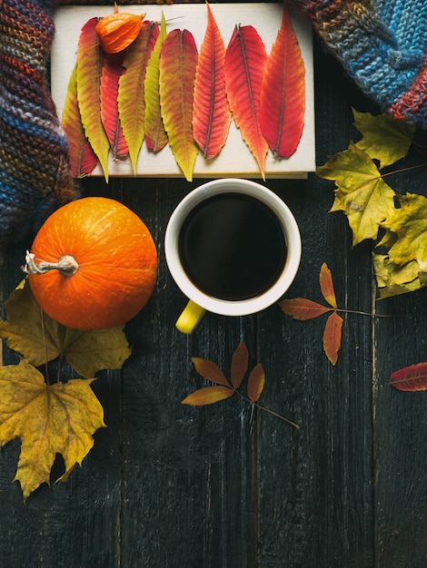 Intimità d'autunno. una tazza di caffè, un libro, piccole zucche e foglie di autunno luminose