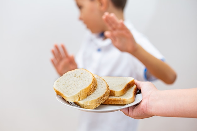 Intolleranza al glutine e concetto di dieta. Il bambino rifiuta di mangiare il pane bianco.