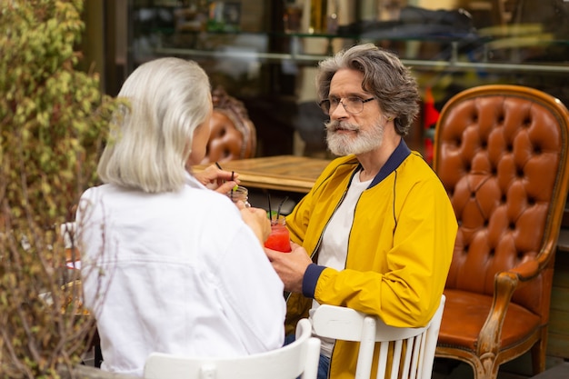 Intrattenere un'idea. Uomo barbuto immerso nei suoi pensieri durante il pranzo con sua moglie in un caffè di strada.