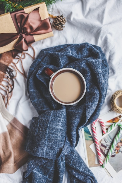 Inverno accogliente. Tazza di caffè, biscotti, regalo, ramo di abete, plaid sul letto