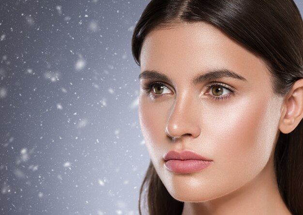 Inverno bellezza pelle donna viso pelle sana bellissimo modello primi piani capelli castani trucco naturale viso. Colore di sfondo. Colpo dello studio.