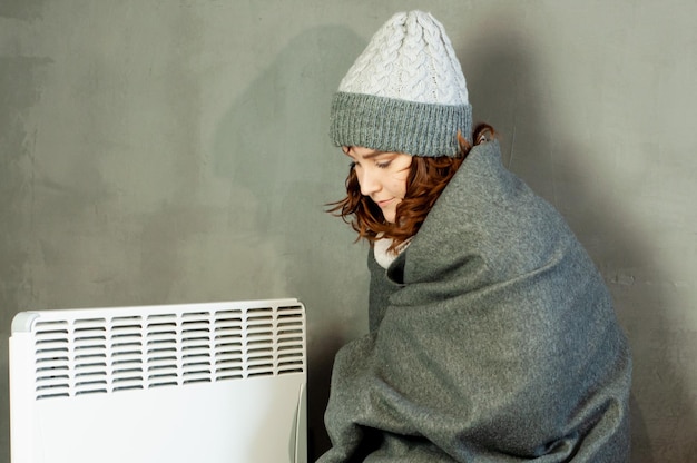 inverno freddo nell'appartamento una ragazza si scalda le mani vicino all'energia della stagione di riscaldamento della batteria del riscaldatore