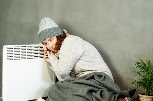 inverno freddo nell'appartamento una ragazza si scalda le mani vicino all'energia della stagione di riscaldamento della batteria del riscaldatore
