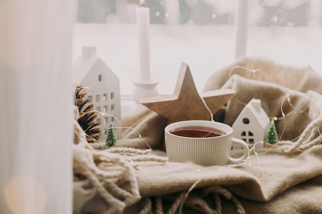 Inverno hygge Calda tazza di tè candele illumina eleganti decorazioni natalizie alla finestra Casa accogliente