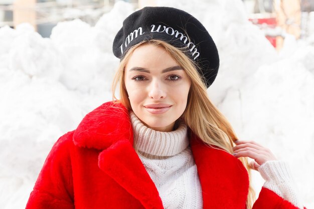 Inverno, moda, concetto di persone - moda Ritratto di una giovane e bella donna cammina per la città sorridente pelliccia rossa close-up fiocchi di neve freddo inverno, respirare aria fresca al giorno d'inverno gelo. tramonto