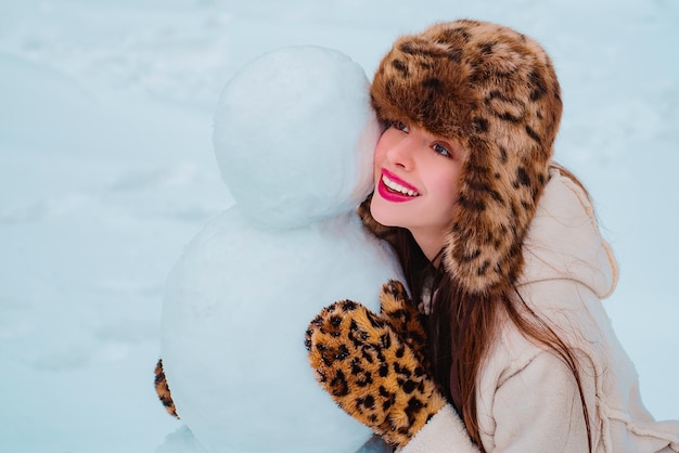 Inverno ritratto di giovane bella donna nel giardino di neve rendere felice il pupazzo di neve inverno donna ritratto hap