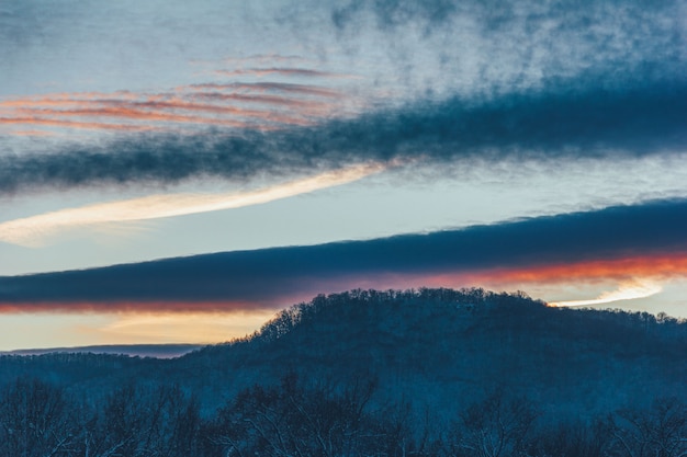 Inverno sera paesaggio pittoresco con collina e cielo nuvoloso