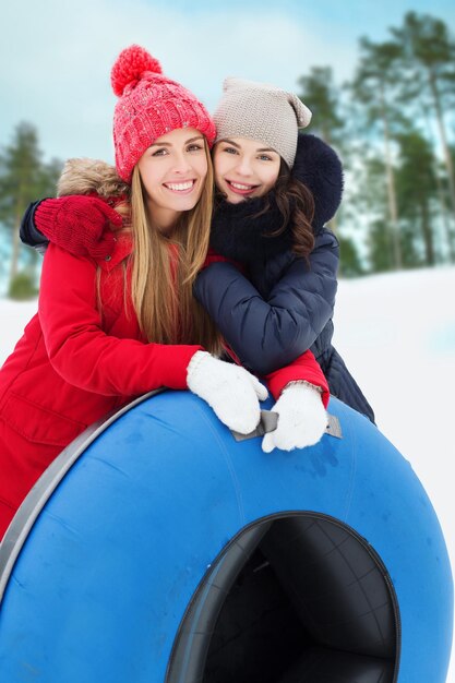 inverno, tempo libero, sport, amicizia e concetto di persone - amiche felici con tubi di neve che si abbracciano all'aperto