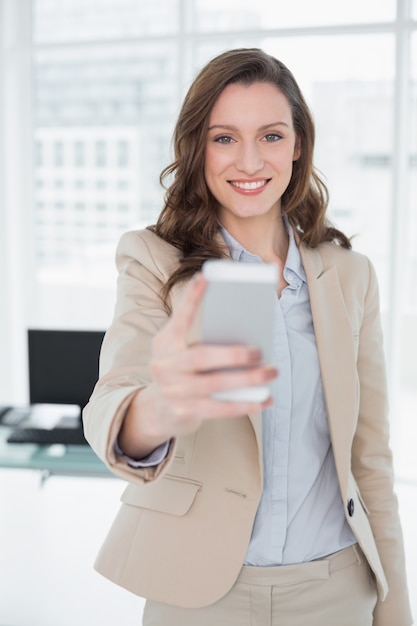 Invio di messaggi di testo elegante sorridente della donna di affari in ufficio