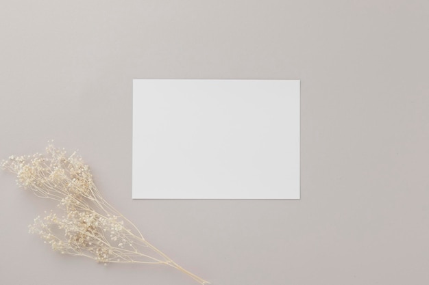 Invito biglietto di auguri vuoto Mockup 5x7 su busta marrone con fiori secchi su sfondo beige mockup piatto