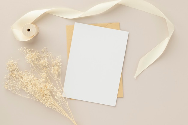 Invito biglietto di auguri vuoto Mockup 5x7 su busta marrone con fiori secchi su sfondo beige mockup piatto