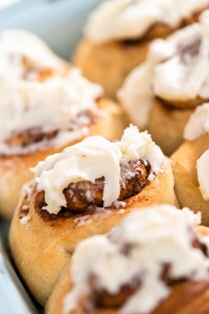 Involtini di cannella appena sfornati con glassa bianca in una teglia blu.