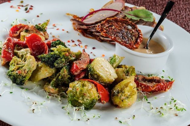 Involtini di filetti di merluzzo arrosto serviti con miglio e broccoli al vapore, carota, cavolini di Bruxelles e zucchine