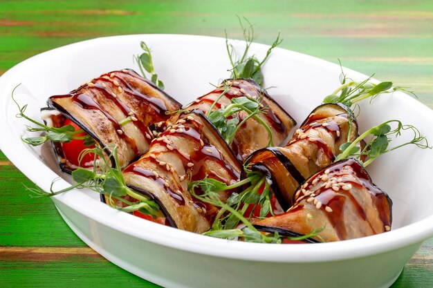 Involtini di melanzane con salsa unagi Su uno sfondo di legno colorato Piatto vegetariano