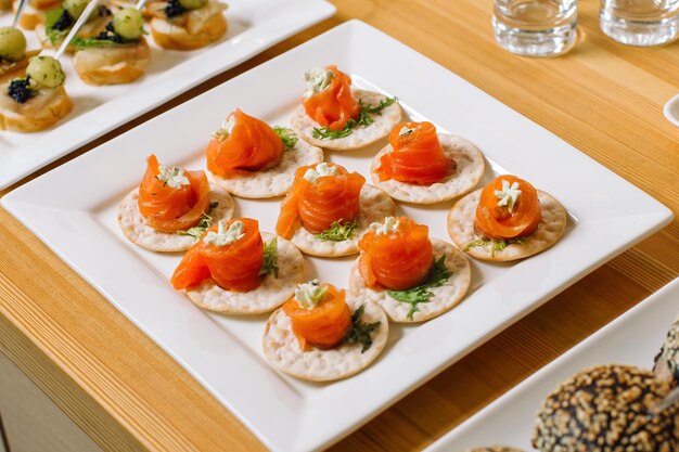 Involtini di salmone affumicato con crema di formaggio Disposti su piccoli pani disposti su un bel piatto bianco