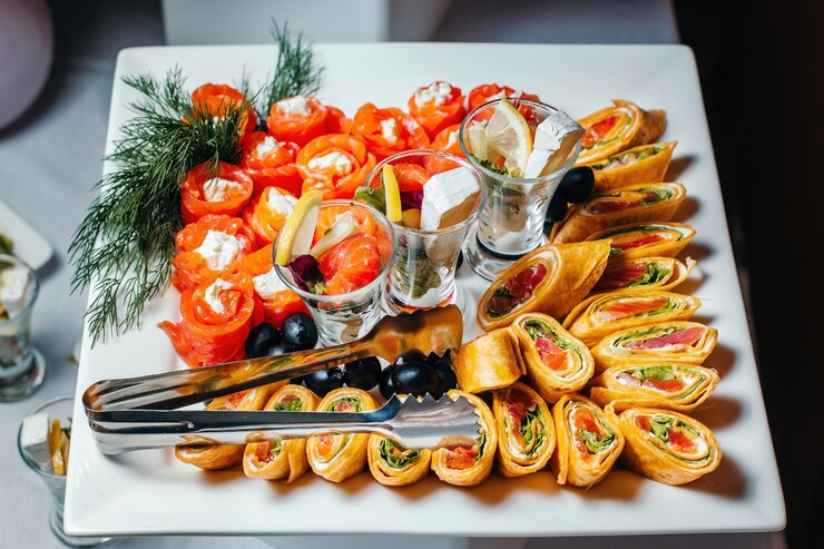 Involtini di salmone ripieni di semi di sesamo cosparsi di formaggio adagiati su una lastra di vetro bianca