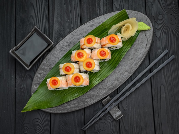 Involtini di sushi con gamberetti caviale tobiko nero e salsa piccante Rotolo di sushi fresco delizioso tradizionale su sfondo nero Menu di sushi Ristorante di cucina giapponese Cibo asiatico