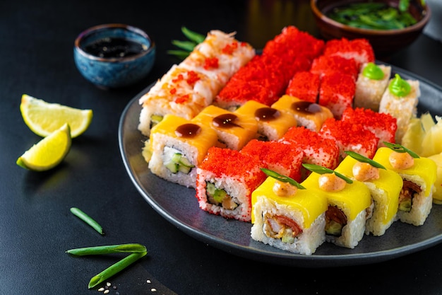 Involtini e sushi tradizionali asiatici con salsa di soia e wasabi serviti su uno sfondo scuro