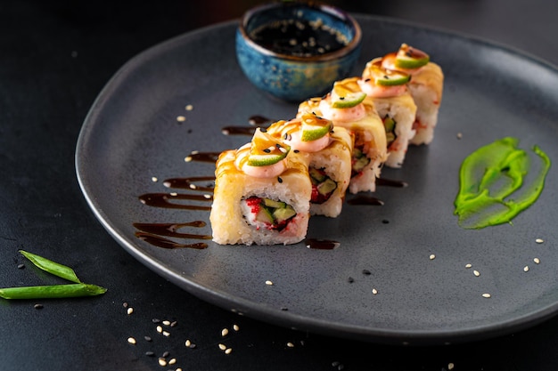 Involtini e sushi tradizionali asiatici con salsa di soia e wasabi serviti su uno sfondo scuro