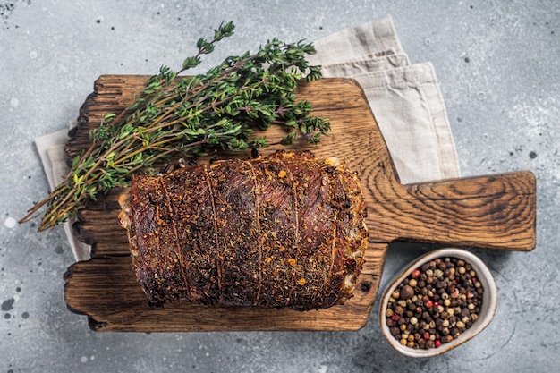 Involtino di maiale arrosto Porchetta farina di maiale su tavola di legno Sfondo grigio Vista dall'alto