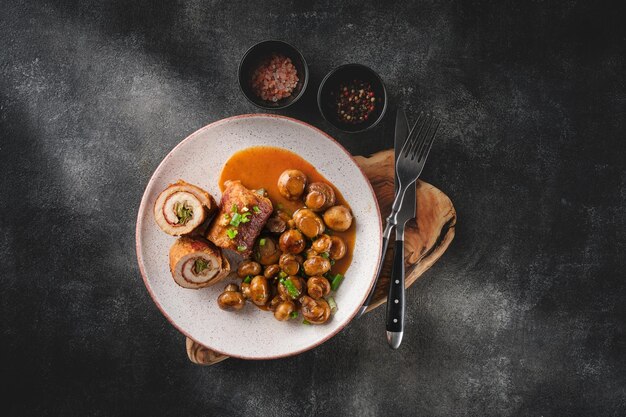 Involtino di maiale con sottaceti e pancetta servito con funghi fritti e cipolle verdi