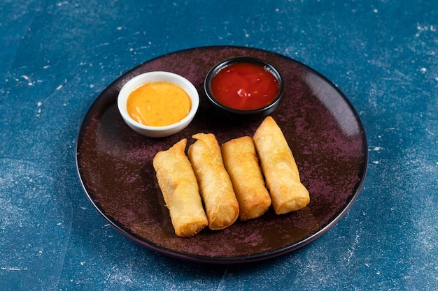 Involtino primavera fritto con salsa di pomodoro e salsa di maionese servito in un piatto isolato sulla vista del tavolo del fastfood