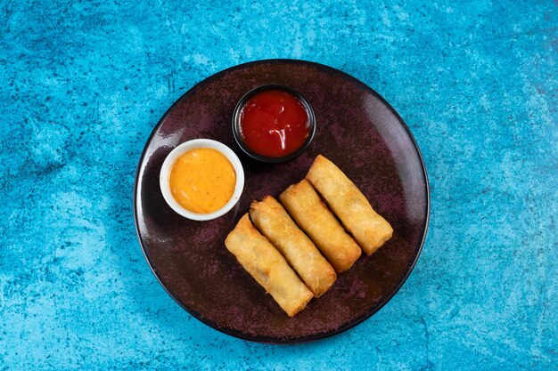 Involtino primavera fritto con salsa di pomodoro e salsa di maionese servito in un piatto isolato sulla vista del tavolo del fastfood