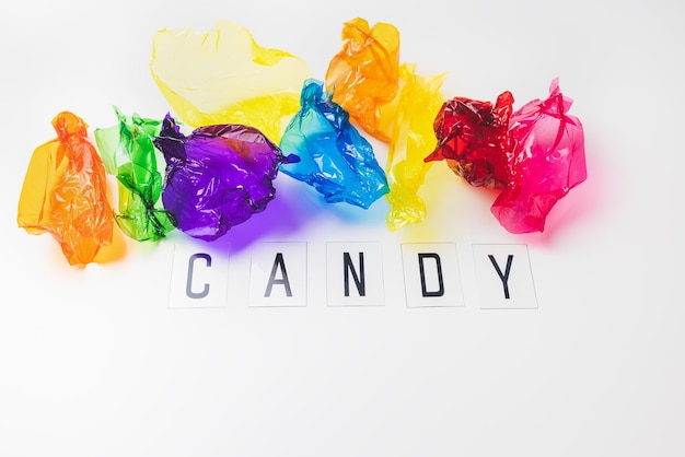 Involucri di caramelle colorate e testo CANDY su sfondo bianco copia spazio