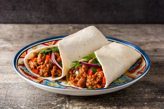 Involucro tipico del burrito messicano con manzo, frijoles e verdure sulla tavola di legno