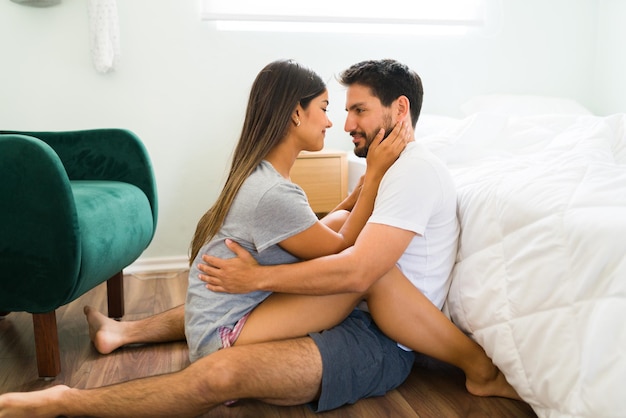 Io sono così innamorato di te. Donna attraente che accarezza il viso del suo ragazzo mentre si guarda negli occhi e condivide un momento romantico in pigiama