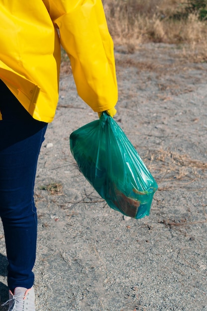 Irriconoscibile giovane donna che raccoglie immondizia nella foresta al mattino. Inquinamento ambientale da plastica. Concetto ecologico volontario