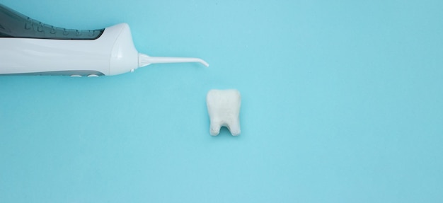 Irrigatore vicino al modello del dente su sfondo blu denti puliti professionali i denti saranno sani