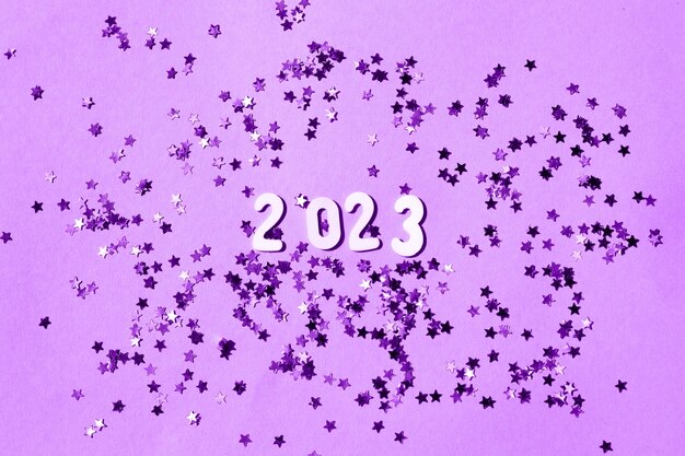 Iscrizione 2023 con numeri in legno su sfondo viola con concetto confettiFestive