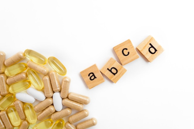 Iscrizione ABCE in cubi di legno su sfondo bianco di diverse pillole