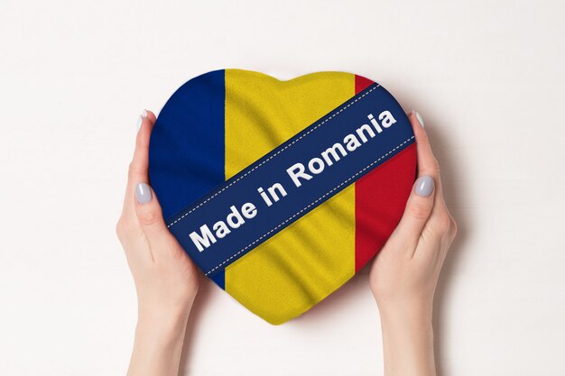 Iscrizione fatta in Romania la bandiera della Romania. Mani femminili che tengono una scatola a forma di cuore.