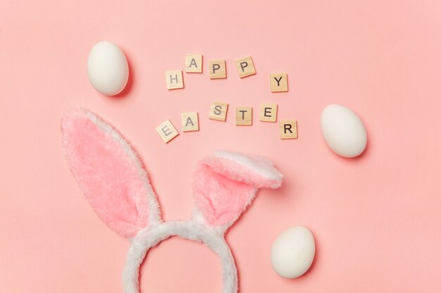 Iscrizione HAPPY EASTER uova decorative orecchie di coniglietto isolate su sfondo rosa