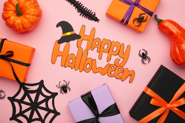 Iscrizione Happy Halloween con scatole regalo ragni su sfondo rosa Vista superiore