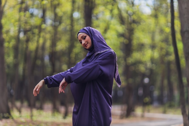 Islamica bella donna in un abito musulmano in piedi su un parco estivo strada sfondo foresta alberi autunnali.giornata mondiale dell'hijab.