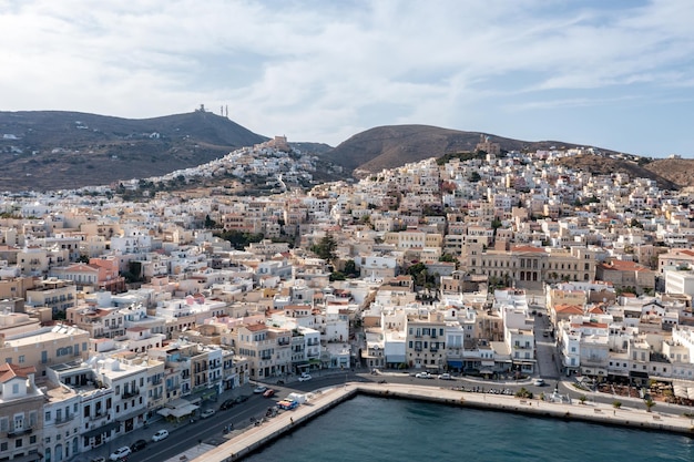 Isola di Siros Grecia vista aerea da drone Ermoupolis e Ano Città di Siros paesaggio cittadino sfondo cielo blu nuvoloso