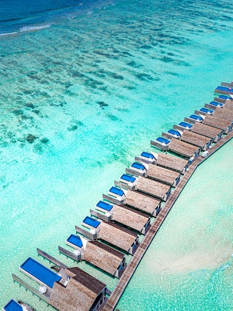 Isola paradisiaca delle Maldive. Paesaggio aereo tropicale, ville di bungalow sull'acqua con molo in legno con vista sul mare