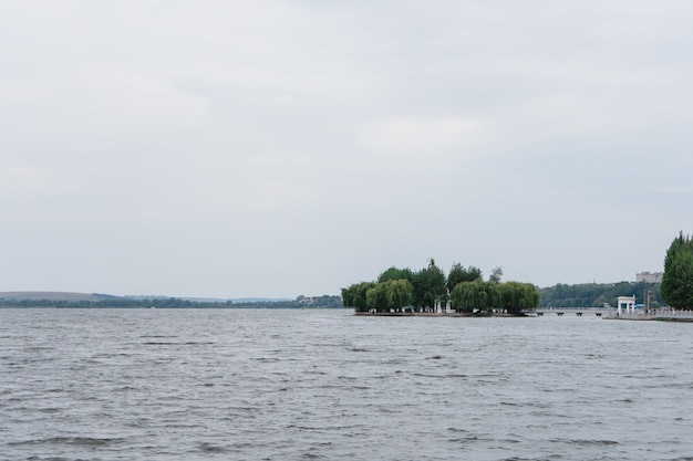 Isola verde tra un grande lago in una giornata di sole. Isola con alberi ad alto fusto sul fiume in una calda giornata estiva.